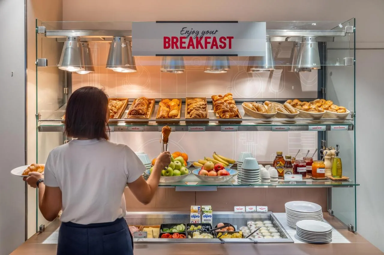 a woman is looking at food in a refrigerator at Point A Hotel Glasgow in Glasgow