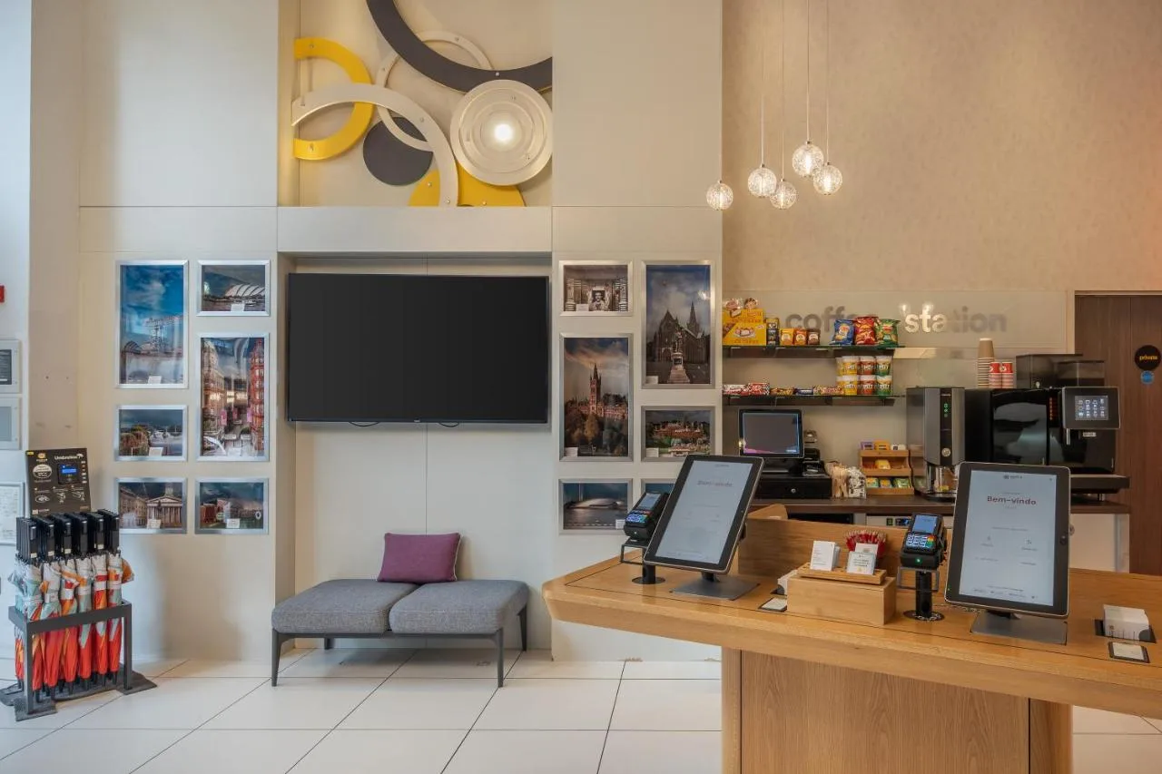 a store with a counter with a tv and a chair at Point A Hotel Glasgow in Glasgow