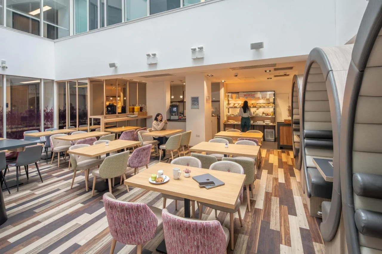 a restaurant with tables and chairs and a cafeteria at Point A Hotel Glasgow in Glasgow